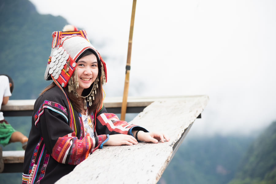 mujer china sonriendo en la proa de un barco mientras observa el paisaje nevado de Yunnuan, China.